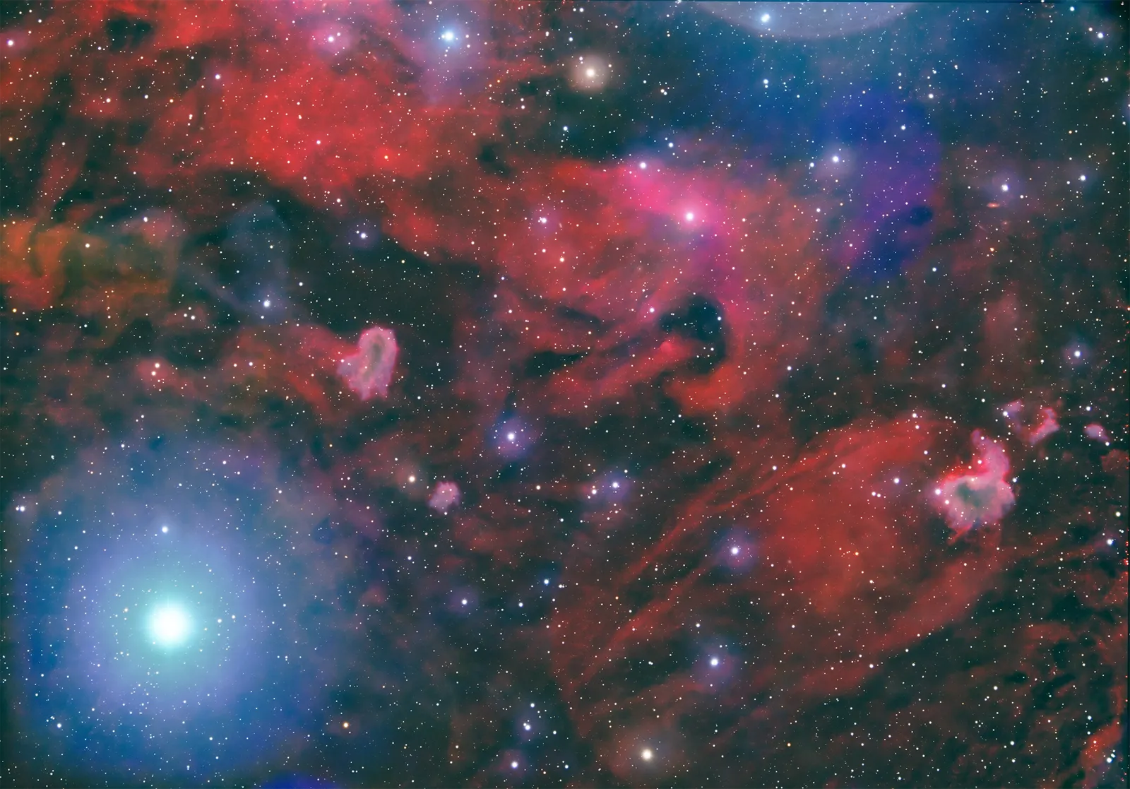 LBN 913, a sprawling red emission nebula in Cepheus with dark dust lanes and a bright blue foreground star