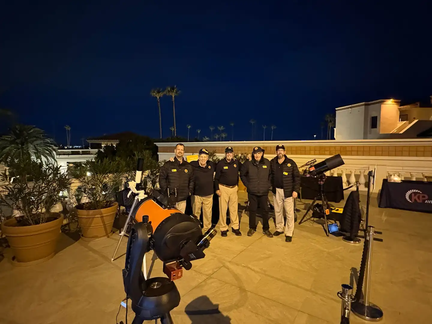 PAS members and telescopes set up on an outdoor terrace at dusk, ready for an observing session