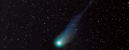 A green comet with a long tail against a starfield