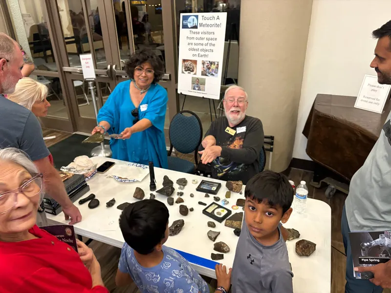 Kids and presenters at a Touch a Meteorite table, with real meteorite specimens laid out