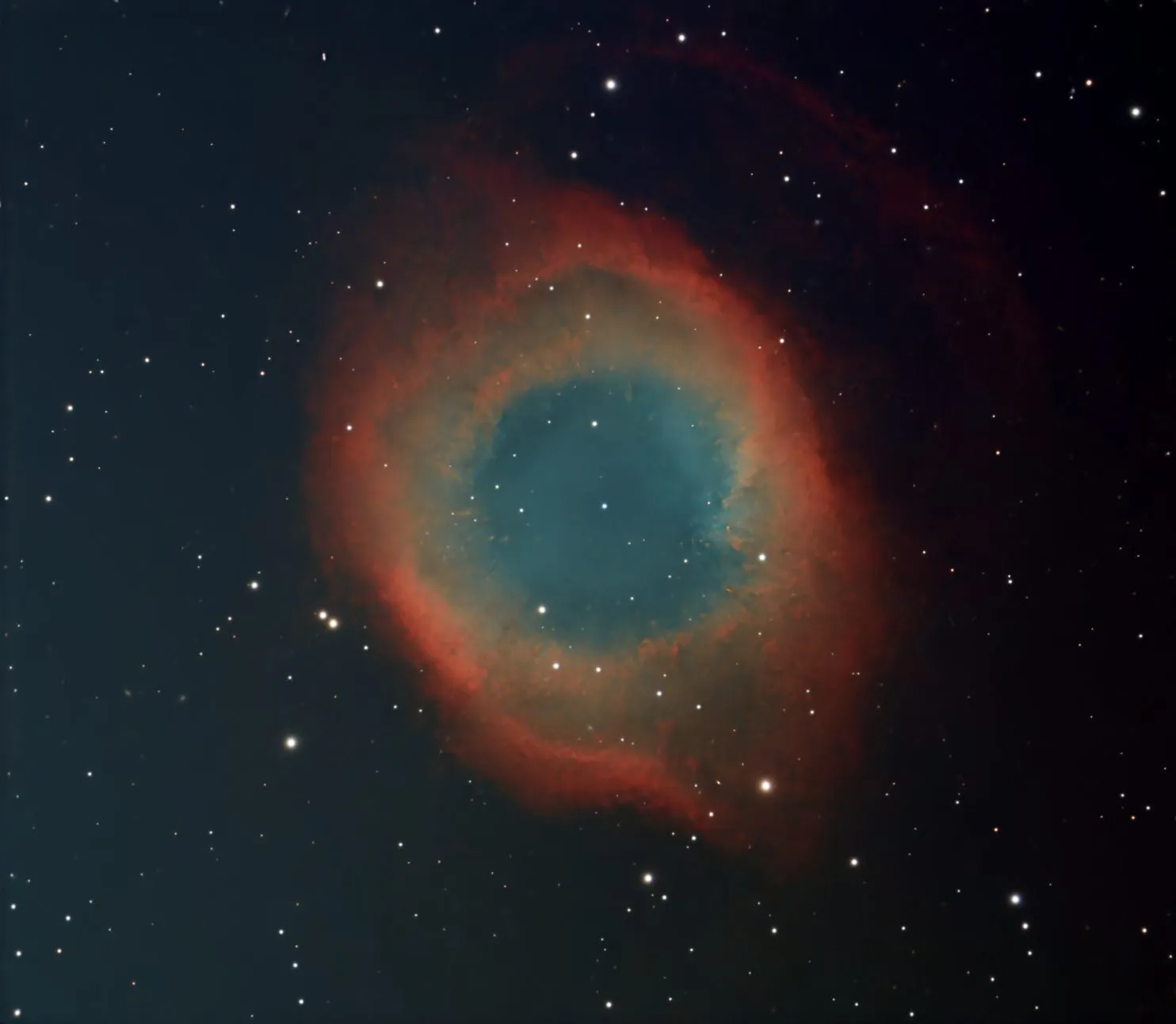 NGC 7293, the Helix Nebula, a glowing ring of red and blue-green gas surrounding a dying star