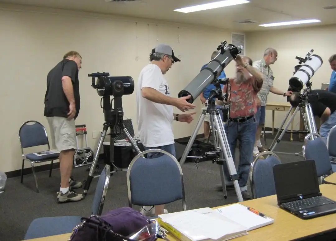 A row of loaner telescopes set up indoors at a PAS event