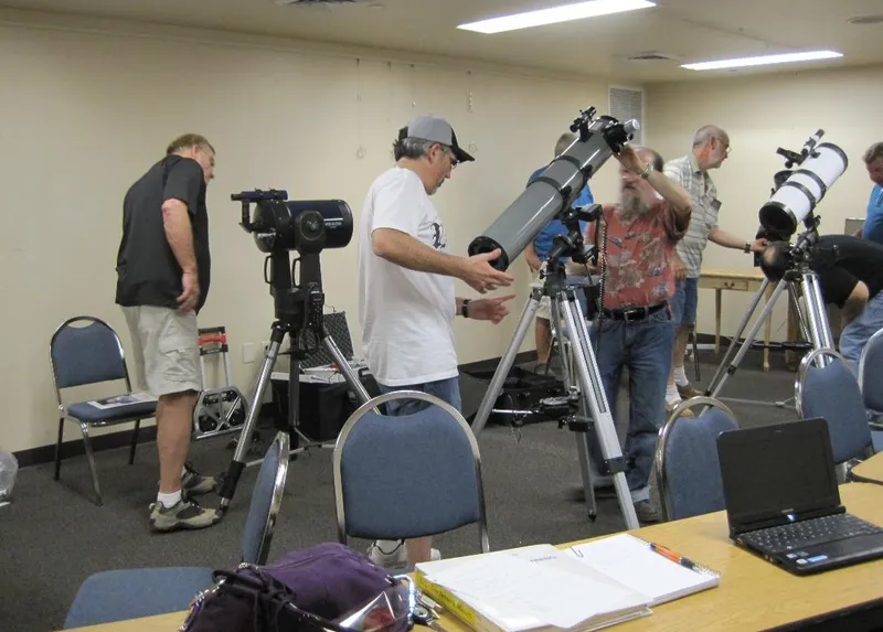 PAS members helping attendees set up and align telescopes at an indoor workshop
